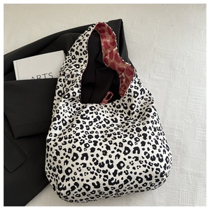 Detail of a leopard print tote bag with reddish-brown lining and soft fabric texture