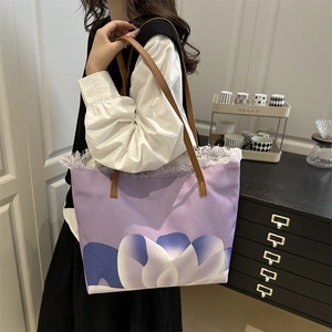 Large purple canvas tote bag with floral print and brown leather handles on shoulder