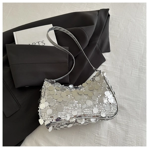 Close-up of silver sequin shoulder bag with metallic luster on black blazer