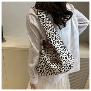 Detail of leopard print canvas tote with fashion patch and red checkered bow decoration