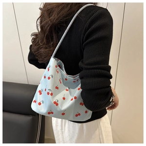 Détail du sac croissant bleu clair avec imprimé cerises pour un look décontracté chic