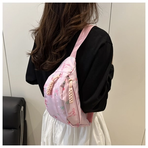 Detalle de riñonera rosa claro con estampado de rosas y cremalleras de cordón trenzado