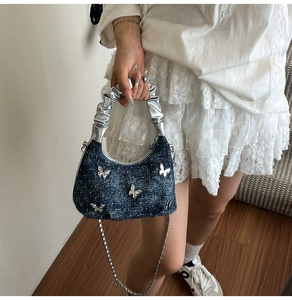 Détail du sac en jean bleu avec patchs papillon argentés et poignée métallisée