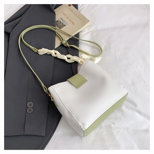 Detail of contrast color bucket bag with green leather trim and silk scarf strap