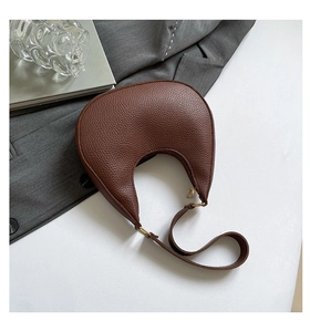 Detail view of brown pebbled leather crescent bag with elegant gold hardware