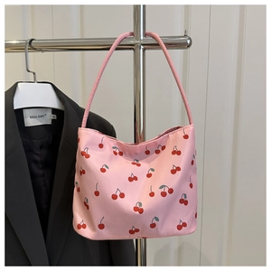 Gros plan d'un sac cabas rose avec motif cerises rouges et bandoulière robuste assortie