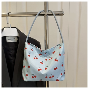 Détail du sac cabas bleu clair avec motifs cerises rouges et fine bandoulière