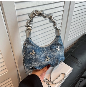 Détail du sac à main en denim bleu avec papillons argentés et poignée style chouchou