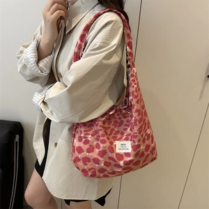 Pink leopard print canvas tote bag with side bow detail shown in a fashion lifestyle setting