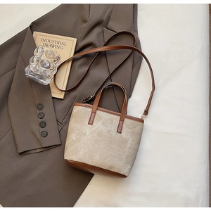 Overhead view of a canvas and brown leather bucket bag with an adjustable strap