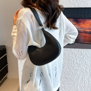 Minimalist black crescent shoulder bag with lychee texture shown on a female model