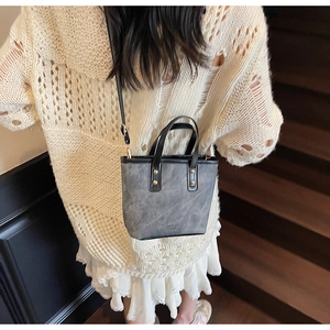 Detailed back view of a grey faux leather crossbody bag with vintage matte texture