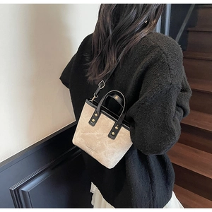 Detail of a chic two-tone tote bag featuring golden rivets and premium leather handles