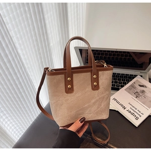 Detail of canvas bag with brown leather handles, metal rivets and debossed logo