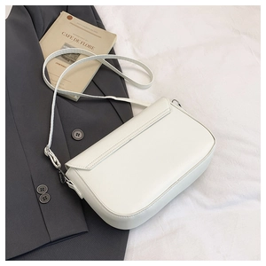 White leather saddle bag on gray blazer with a Cafe de Flore book, chic aesthetic