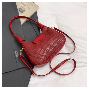 Detail of red woven texture shoulder bag with gold hardware and stylish crescent design