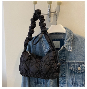 Detail einer schwarzen Stepptasche mit Raffgriff hängend neben einer Jeansjacke