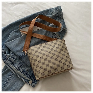 Close-up of beige canvas bucket bag with logo pattern and branded wide fabric strap