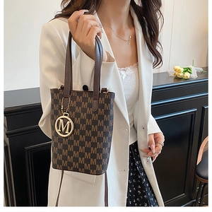 Detail of vintage patterned tote bag with gold M-letter charm and brown handles
