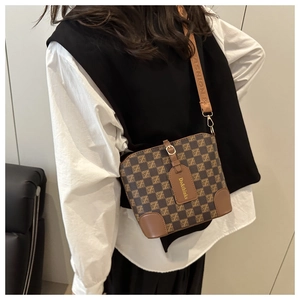 Detail of brown checkered bucket bag with leather reinforced corners and fashion strap