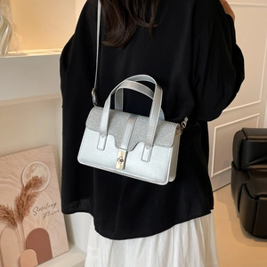 Silver glossy square handbag with sequin detail and shoulder strap shown in a modern setting