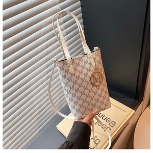 Close-up of a vintage monogram print tote bag with a golden M-letter charm and fine leather texture