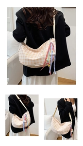 Detalle del bolso de media luna a cuadros con bordados lindos y cintas de colores