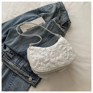 Gros plan du sac hobo blanc montrant la texture plissée et la fine bandoulière