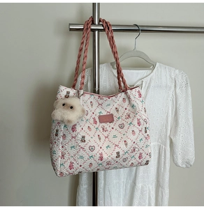 Close-up of white quilted tote bag with cute cartoon prints and pink woven handles