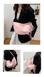 Detalle de bolso hobo a cuadros rosas con bordado de corazón y colgante de borlas de colores