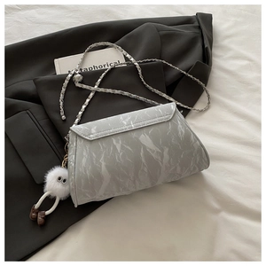 Detail of light grey marble pattern crossbody bag with silver chain and plush charm