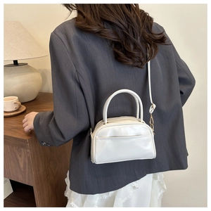 Vue de dos d'un sac oreiller en cuir PU blanc minimaliste porté en bandoulière par un modèle