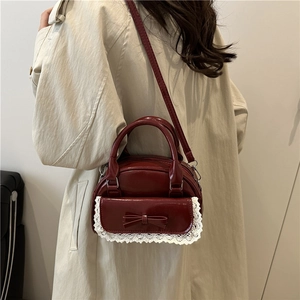 Sac coquillage bordeaux foncé avec dentelle et nœud, porté sur modèle avec bandoulière