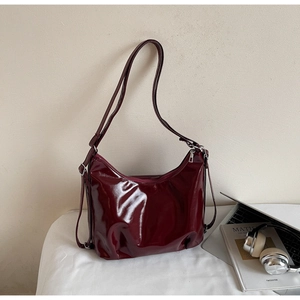 Détail du sac hobo en cuir verni bordeaux brillant avec fermeture éclair en métal