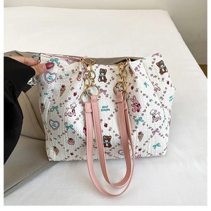 Close-up of a white textured tote with cartoon bears, rabbits, and pink chain strap