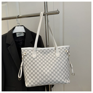 Detail of white tote bag with grey monogram print and gold ring hardware on strap