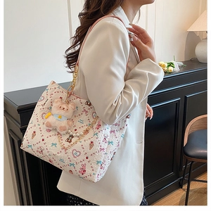 Detail of white cartoon tote bag with pearl chain and brown plush bear charm