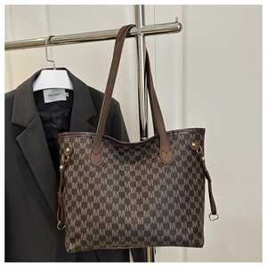 Detail of brown tote bag featuring repeating M letter prints and gold-tone hardware
