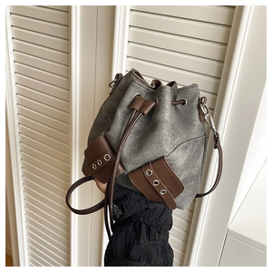 Detailed view of gray washed denim bucket bag with brown leather accents and drawstring
