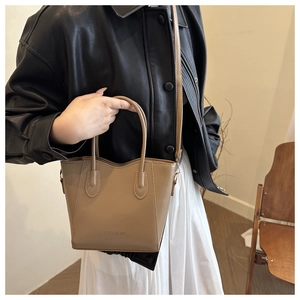 Detail showing the wavy top edge and embossed FASHION logo on khaki leather bucket bag
