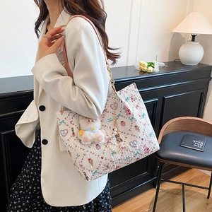 Large cream tote bag with cute cartoon prints and pink leather straps on model
