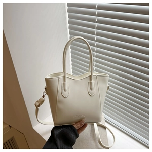 Close-up of a minimalist cream white bucket bag with FASHION logo and smooth texture