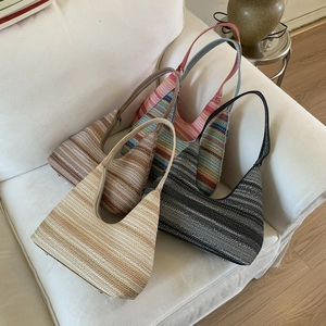 Close-up of four handmade crochet hobo bags in assorted colors on a soft fabric sofa