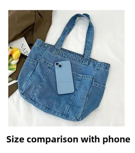 Blue denim tote bag detail showing multi-pocket design with mobile phone for size scale