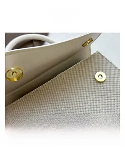 Macro detail of golden magnetic buckle on off-white textured faux leather handbag