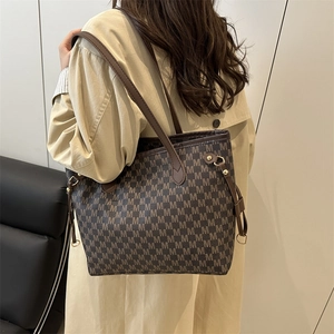 Brown tote bag with all-over M-letter print and slim handles shown on model's shoulder