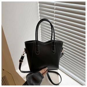 Close-up of black leather bucket bag with embossed FASHION logo and gold hardware