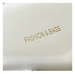 Detail of white lychee grain leather with gold Fashion & Bags lettering and neat stitching