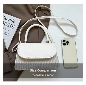 Detail of the elegant white and grey patchwork shoulder bag next to a smartphone