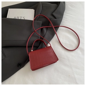 Detailed view of burgundy faux leather crossbody bag with crocodile pattern texture